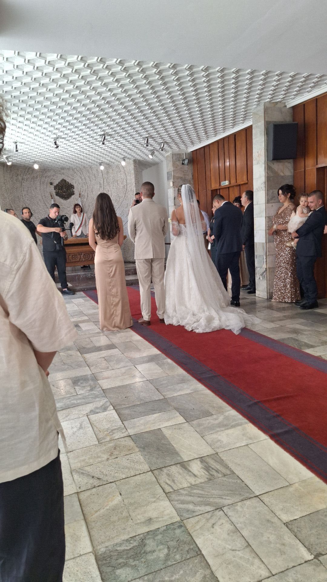 People walking on a red carpet inside a modern building with a white ceiling.