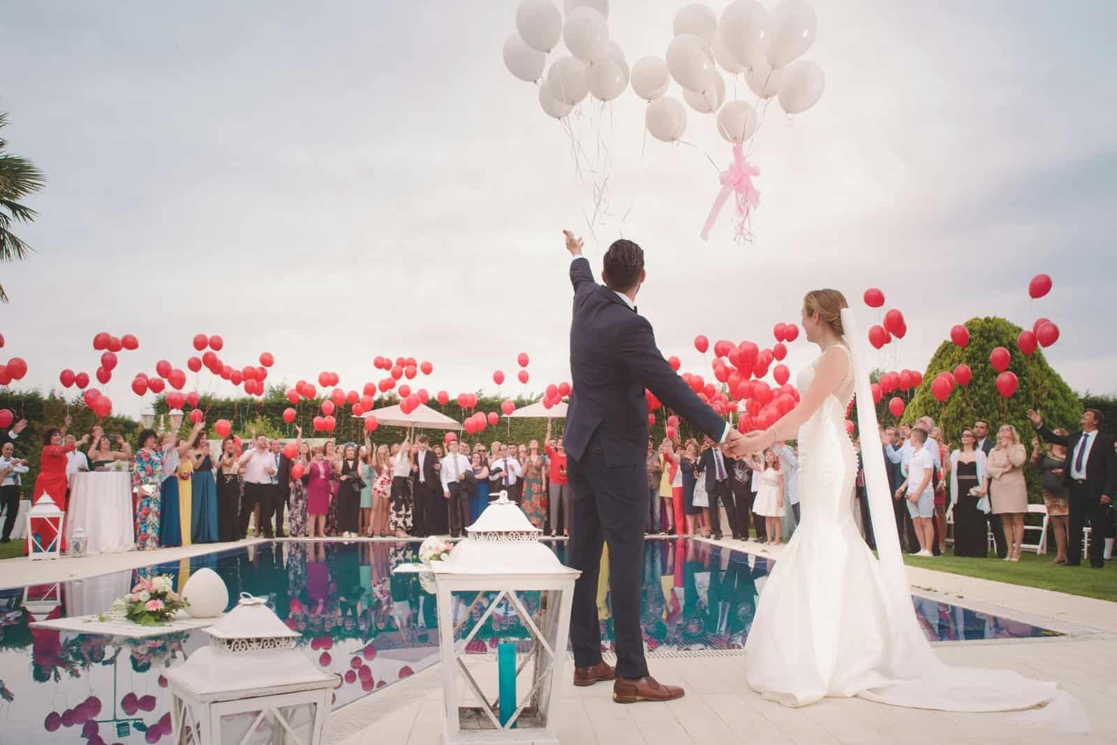 Elegant wedding ceremony with balloons and poolside setting.