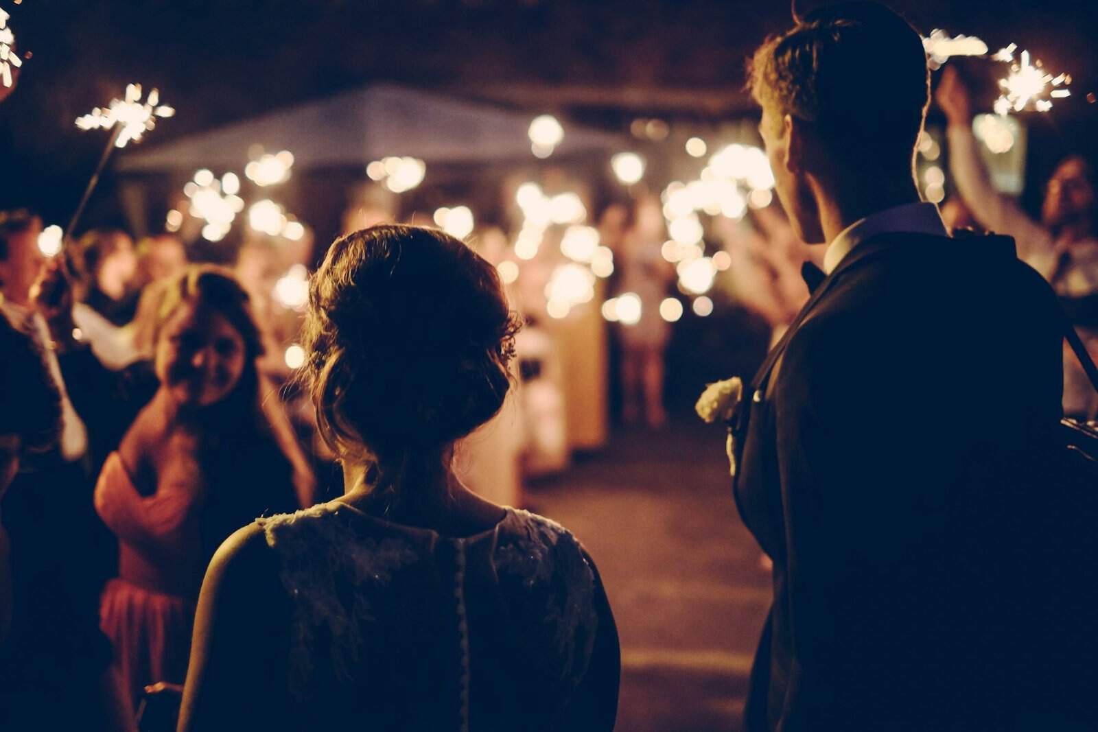 Sparkler celebration at night with a couple and guests in the background.