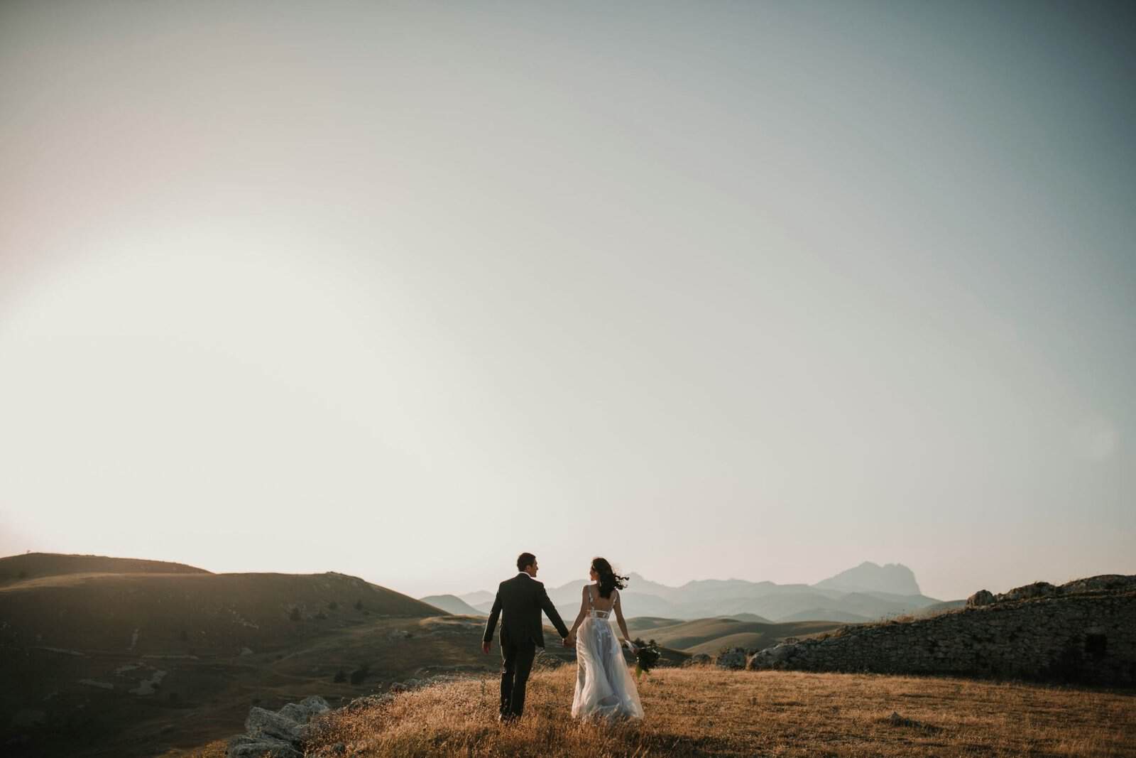 Elegant couple walking in a scenic landscape at sunset, showcasing a Makasa Etch Blueprint design.