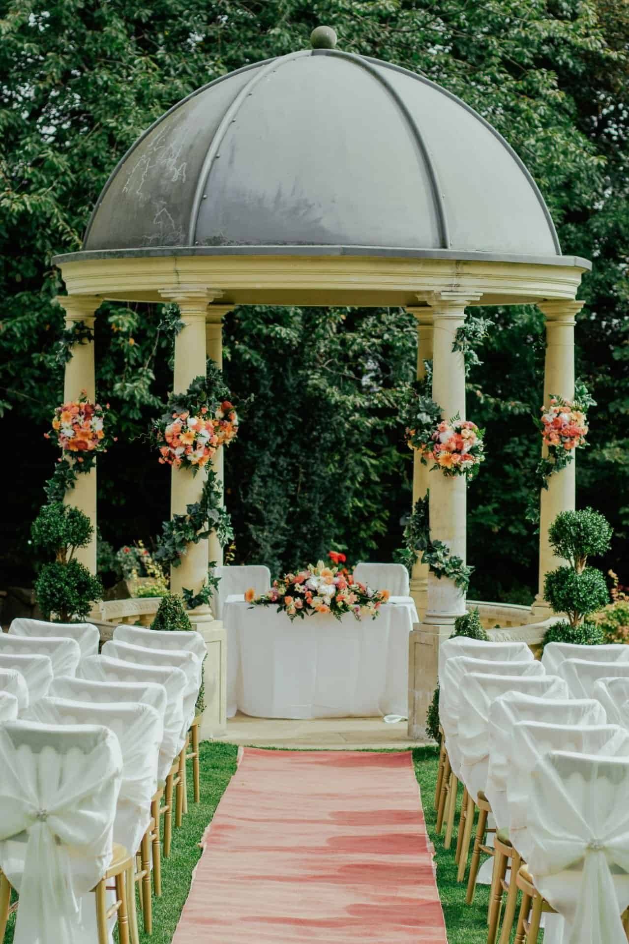 Elegant outdoor wedding altar with floral arrangements and a domed pavilion.