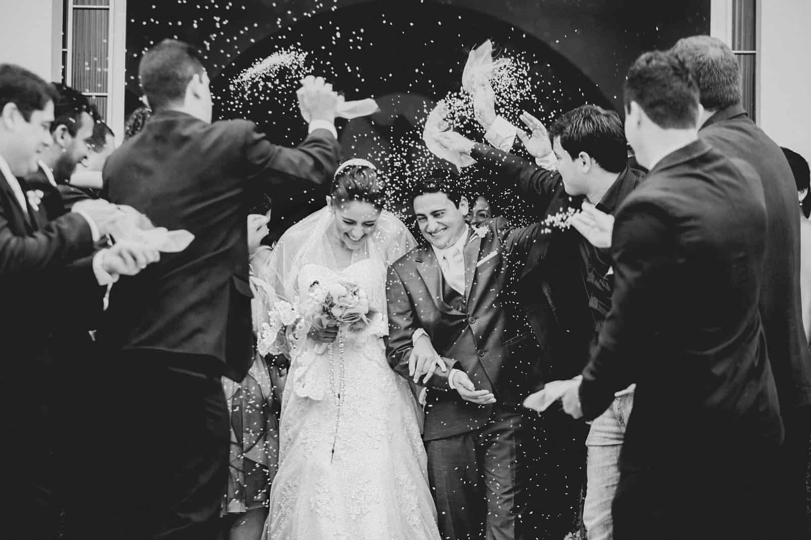 Wedding celebration with guests throwing confetti and a bride and groom smiling.