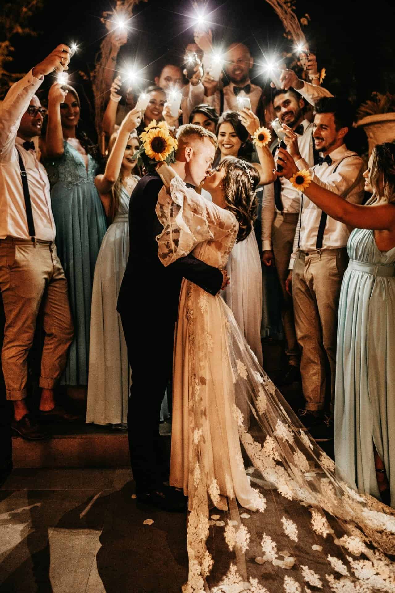 Celebrating a wedding with joyful guests holding sparklers at night.