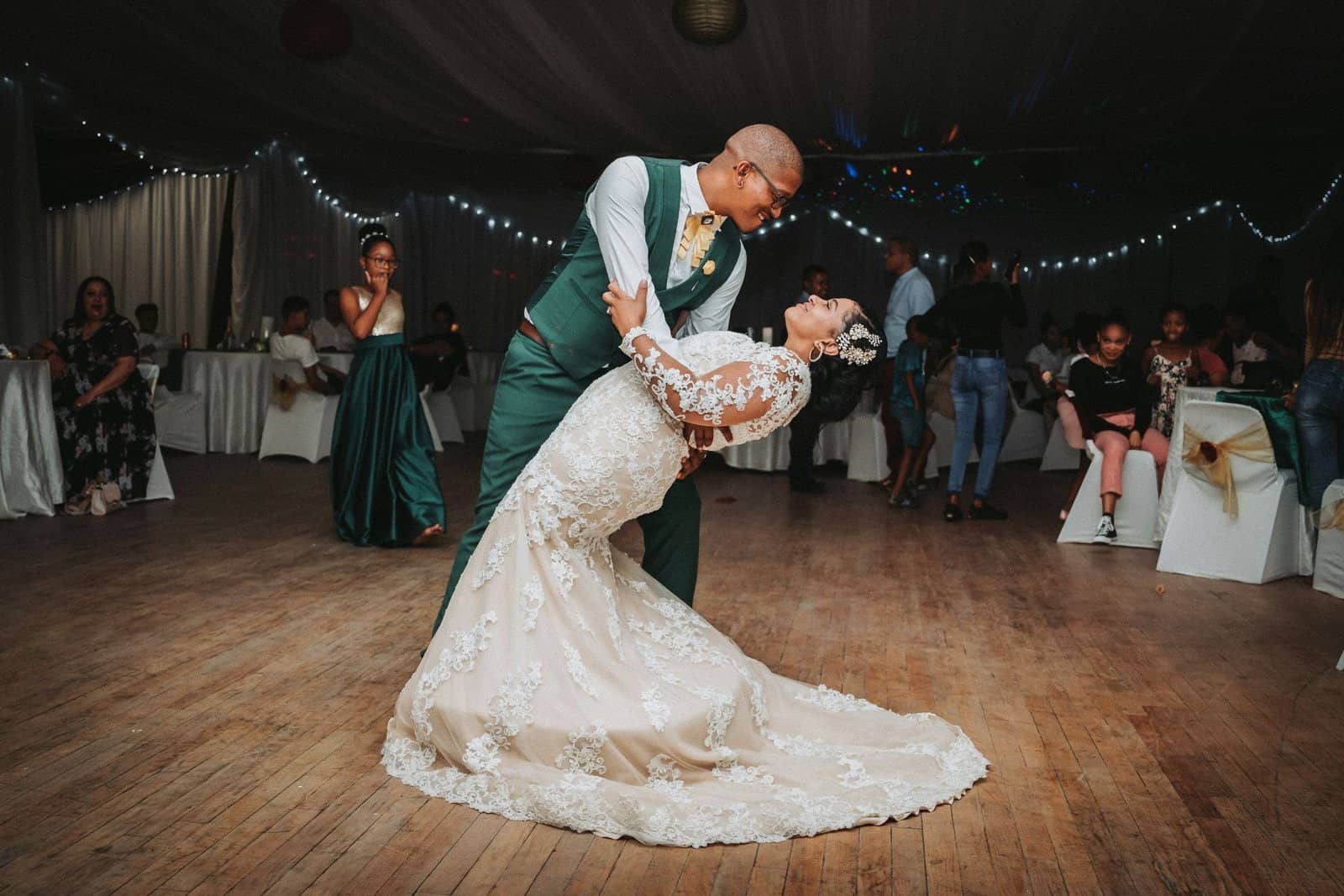 Bride and groom sharing a dance at a wedding reception with string lights overhead.